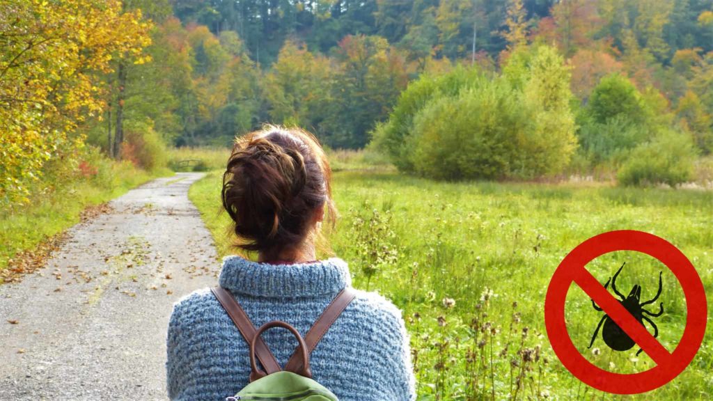 Spaziergängerin auf einem Weg am Wiesenrand, daneben das Verbotszeichen